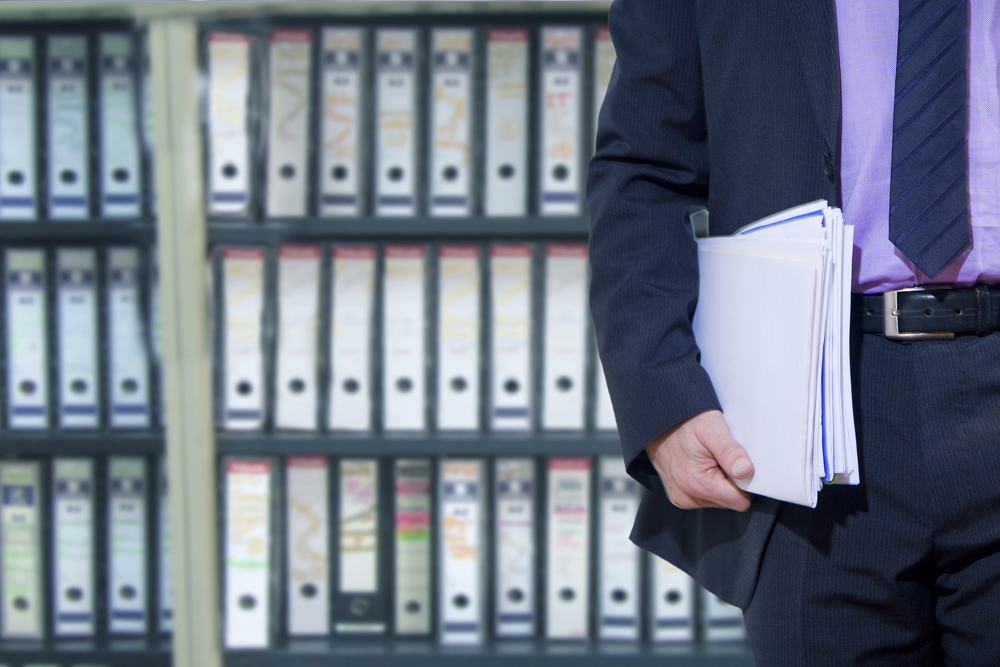 Lawyer carrying some paperwork near a wall of file boxes