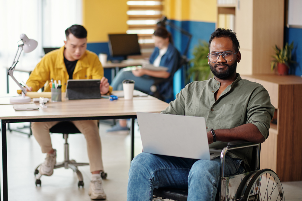 man sat in a wheelchair with a laptop on his knees